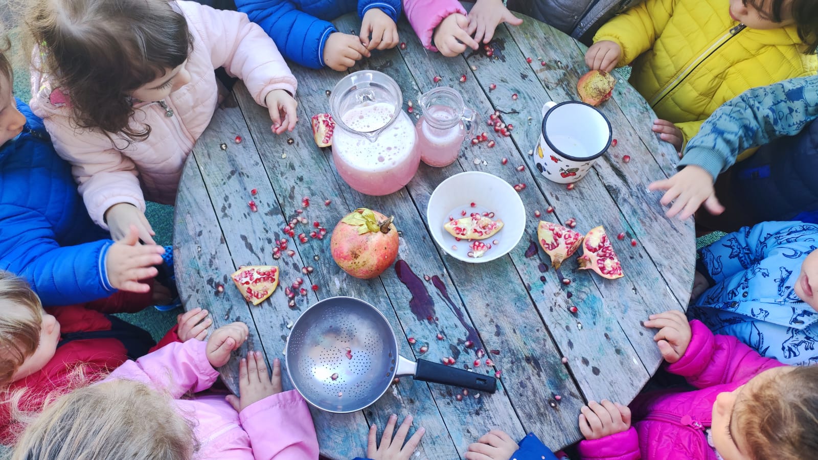 Bambini dell'asilo nido La Coccinella durante un laboratorio all'aperto con le melagrane